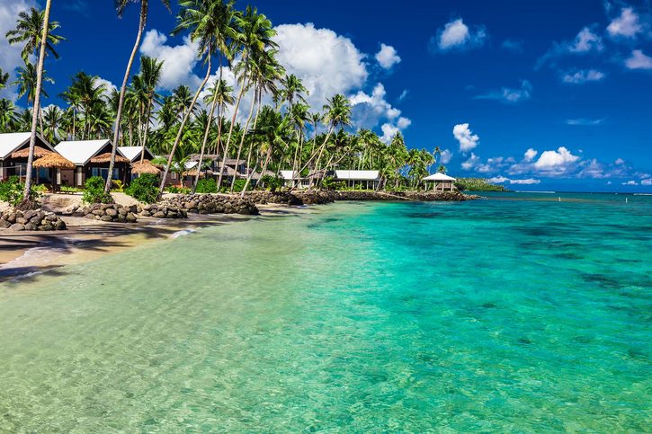 Tropická pláž s kokosovými palmami a vily na ostrově Samoa