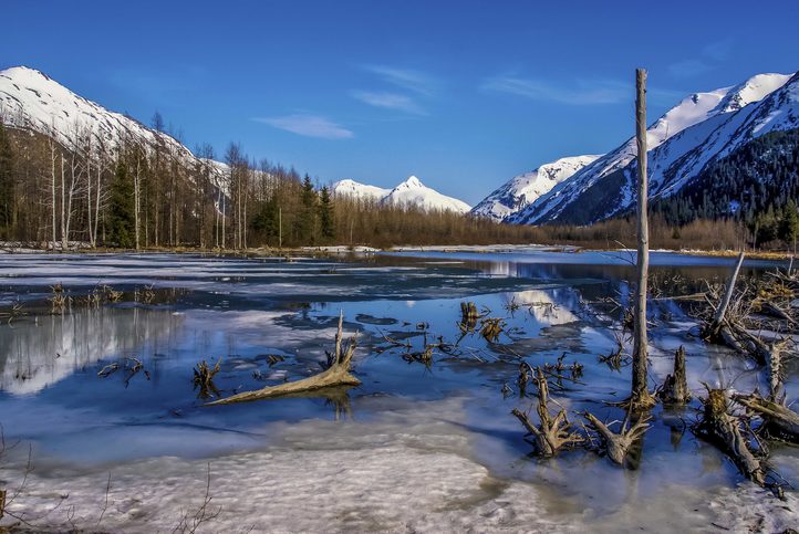 Částečně zamrzlé jezero s pohoří Range Reflected ve Velké aljašské divočině u města Seward, Aljaška