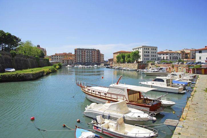 Centrum italského města Livorno s klidným kanálem, podél kterého kotví menší lodě a čluny.