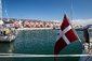 Pohled na přístavní město Skagen s typickými  červenými dřevěnými dánskými stavbami a loděmi. Dánská vlajka v předu